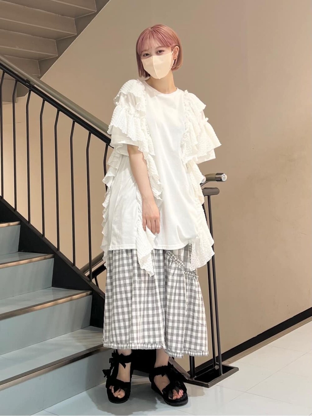 ホワイト系のチュニック、グレー系のスカート、ブラック系のサンダルを着用したレディースの夏コーディネートの3枚目の写真