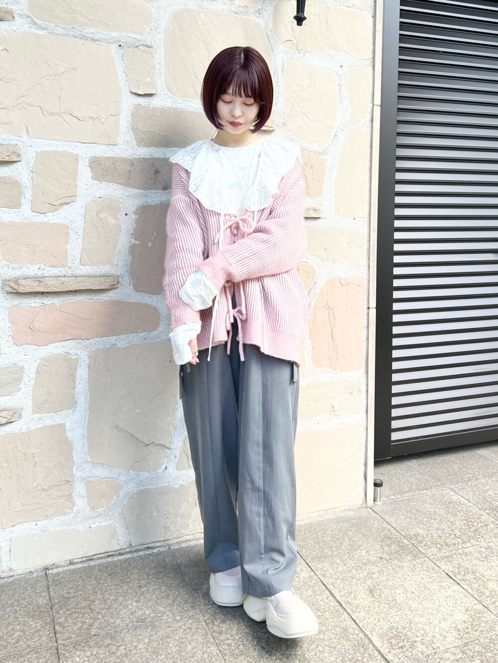 ホワイト系のTシャツ/カットソー、グレー系のスラックス、ピンク系のカーディガン/ボレロを着用したレディースの秋コーディネートの2枚目の写真