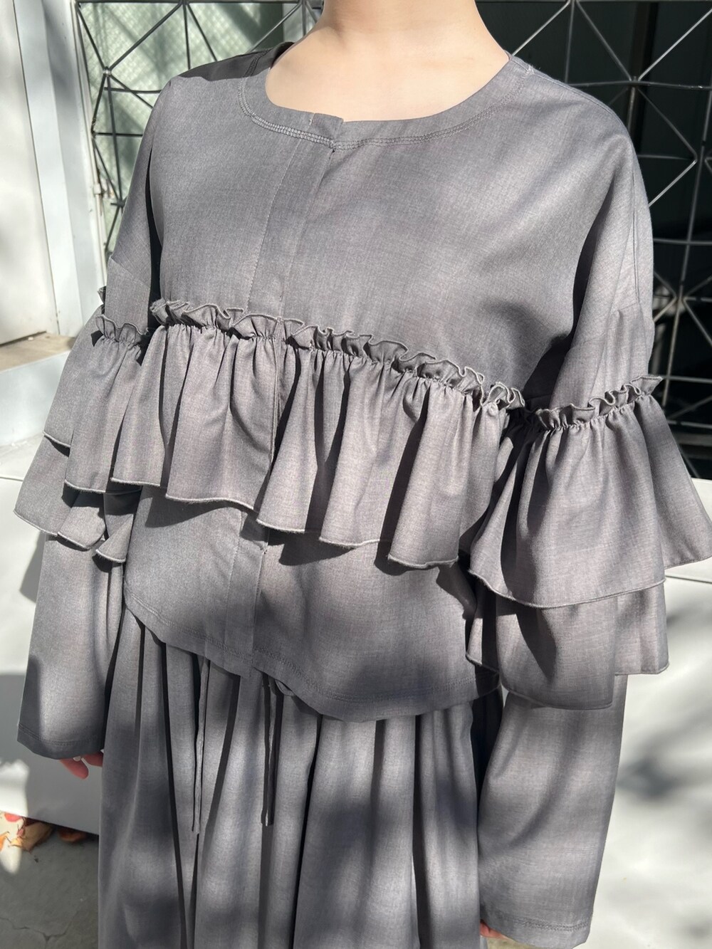 グレー系のテーラードジャケット、グレー系のスカート、ブラック系のパンプスを着用したレディースの秋コーディネートの7枚目の写真