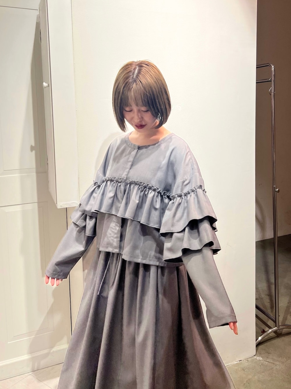 グレー系のテーラードジャケット、グレー系のスカート、ブラック系のパンプスを着用したレディースの秋コーディネートの9枚目の写真