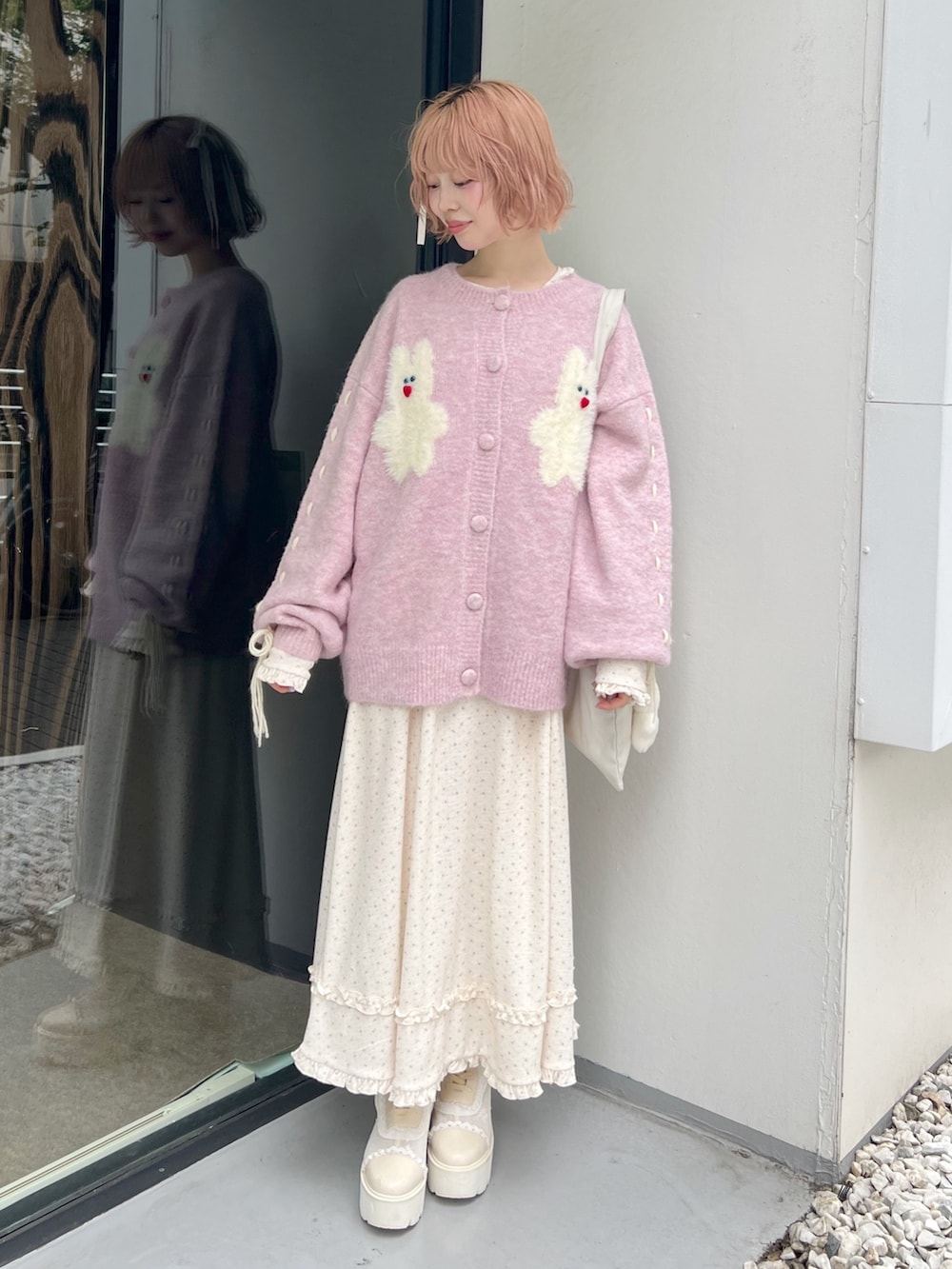 ホワイト系のブーツ、ピンク系のカーディガン/ボレロ、ホワイト系のトートバッグを着用したレディースの秋コーディネートの9枚目の写真