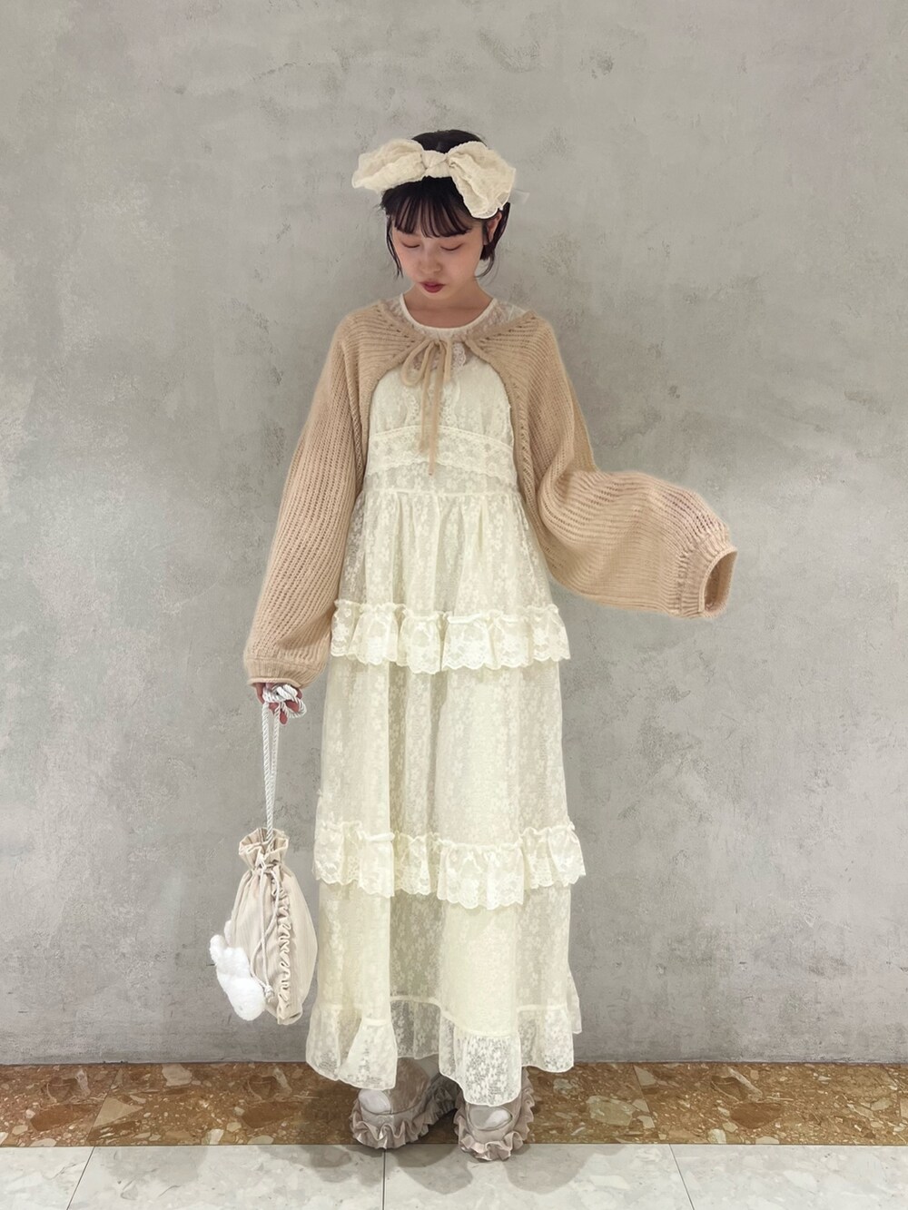 ベージュ系のカーディガン/ボレロ、ホワイト系のワンピース、ホワイト系のショルダーバッグを着用したレディースの夏コーディネートの4枚目の写真