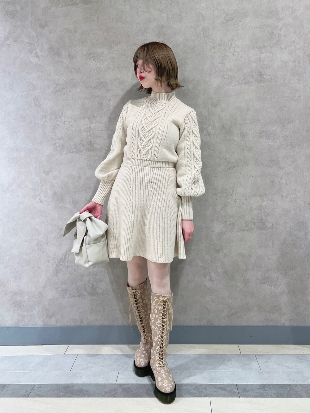 ホワイト系のワンピース、ベージュ系のブーツ、ホワイト系のショルダーバッグを着用したレディースの冬コーディネートの2枚目の写真