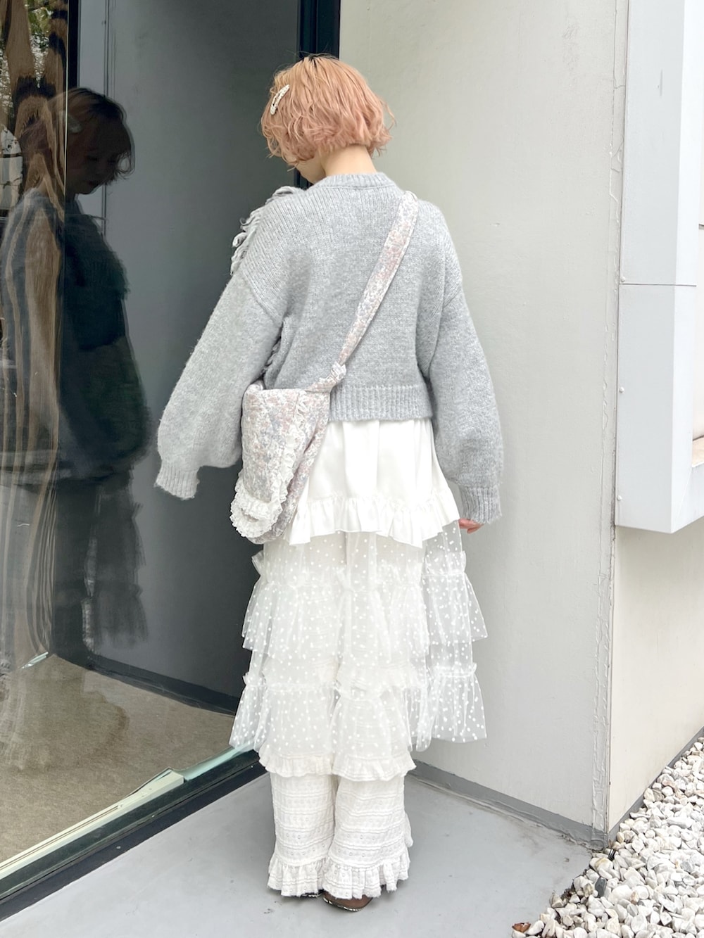 グレー系のニット/セーター、ホワイト系のショルダーバッグ、ホワイト系のスカートを着用したレディースの秋コーディネートの3枚目の写真