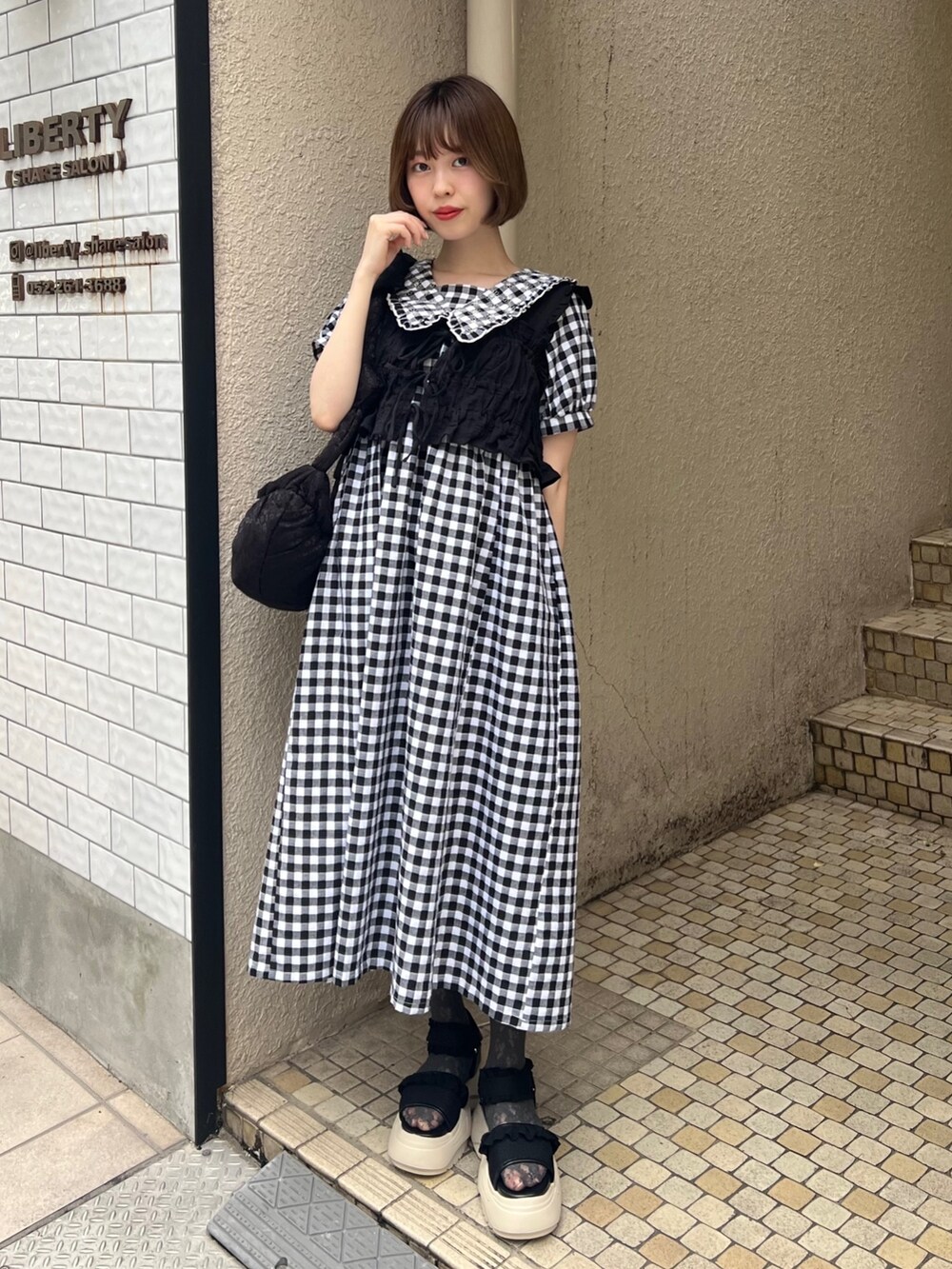 ブラック系のベスト、ブラック系のサンダル、ブラック系のワンピースを着用したレディースの夏コーディネートの3枚目の写真