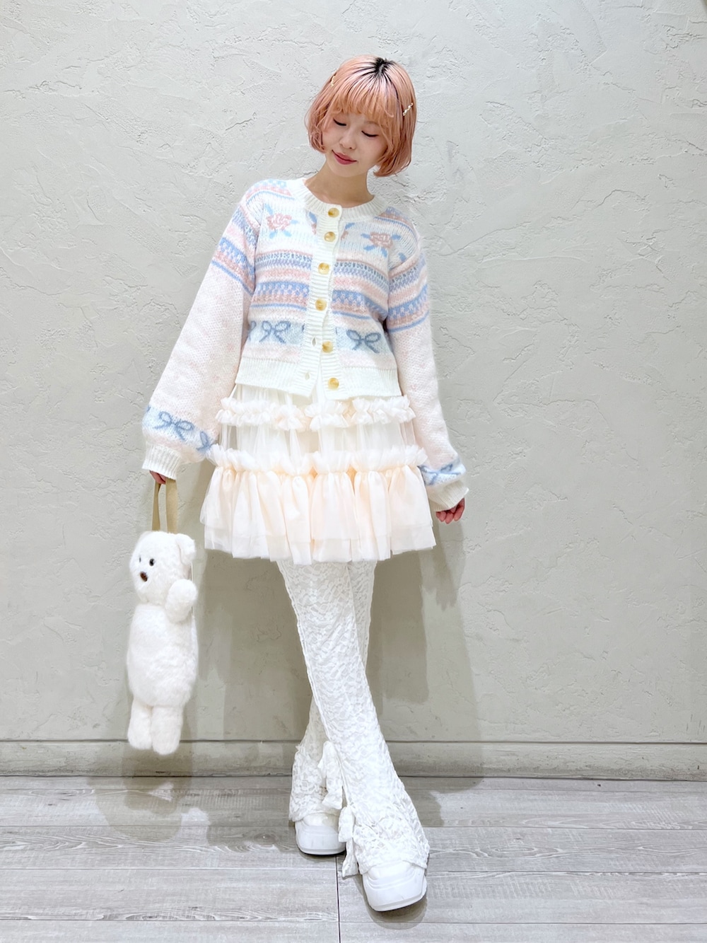 ホワイト系のカーディガン/ボレロ、ピンク系のスカート、ホワイト系のハンドバッグを着用したレディースの秋コーディネートの3枚目の写真