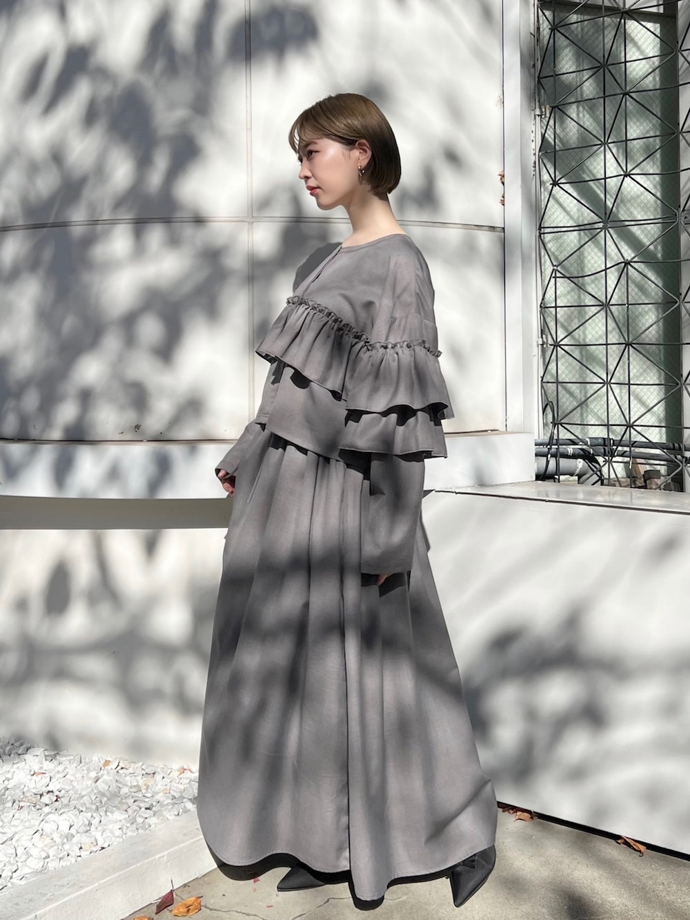 グレー系のテーラードジャケット、グレー系のスカート、ブラック系のパンプスを着用したレディースの秋コーディネートの2枚目の写真