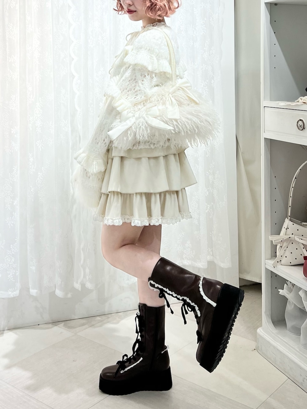 ホワイト系のボストンバッグ、ブラウン系のブーツ、ホワイト系のスカートを着用したレディースの夏コーディネートの5枚目の写真