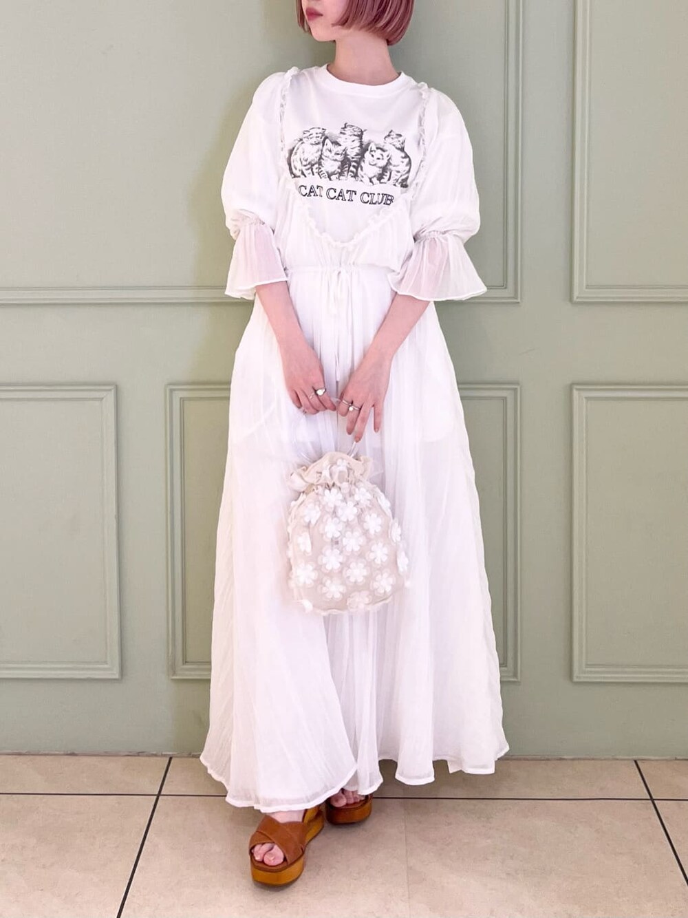 ホワイト系のハンドバッグ、ホワイト系のワンピース、ブラウン系のサンダルを着用したレディースの夏コーディネートの2枚目の写真