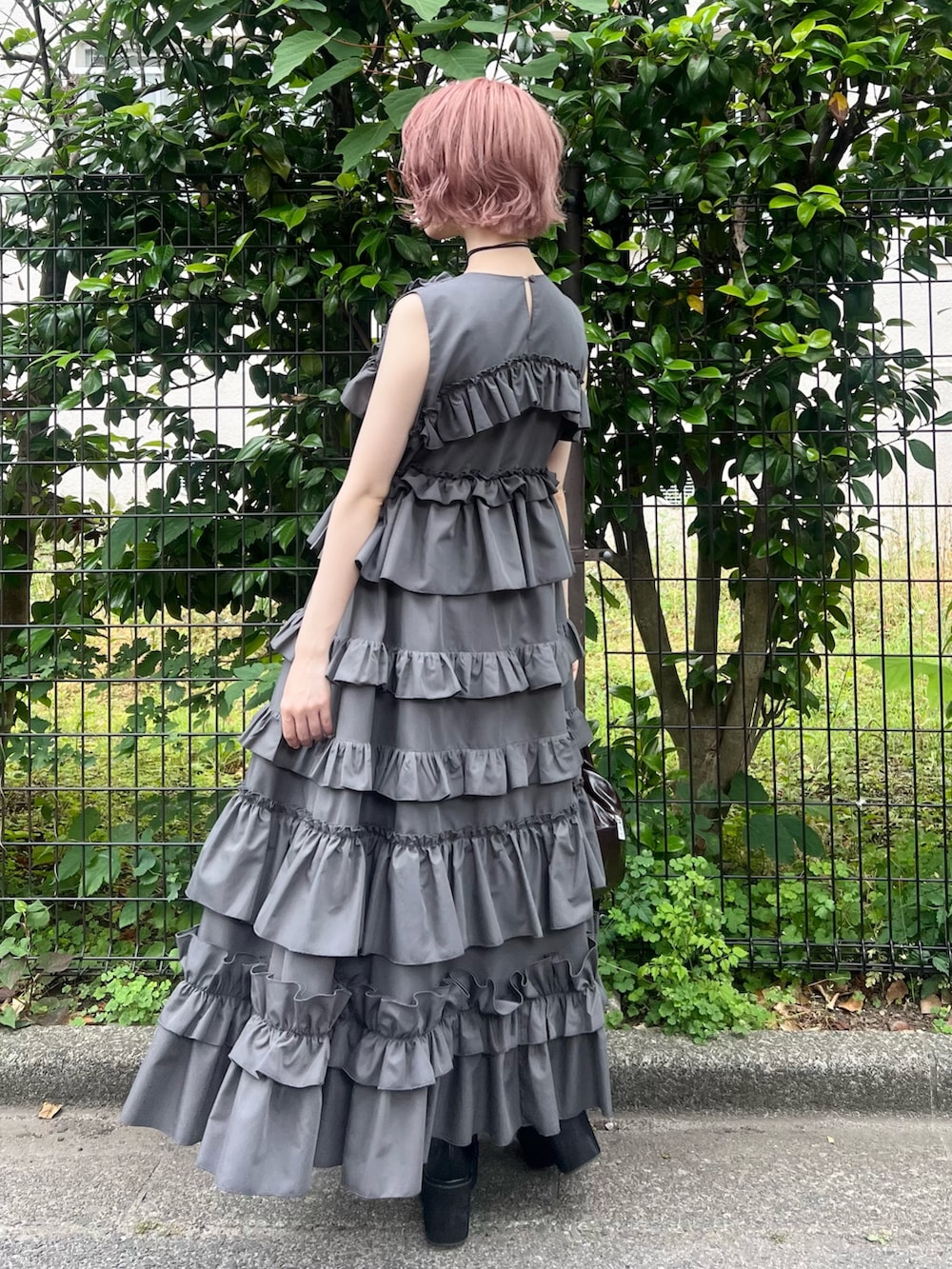 グレー系のワンピース、ブラウン系のハンドバッグ、ブラック系のブーツを着用したレディースの夏コーディネートの3枚目の写真