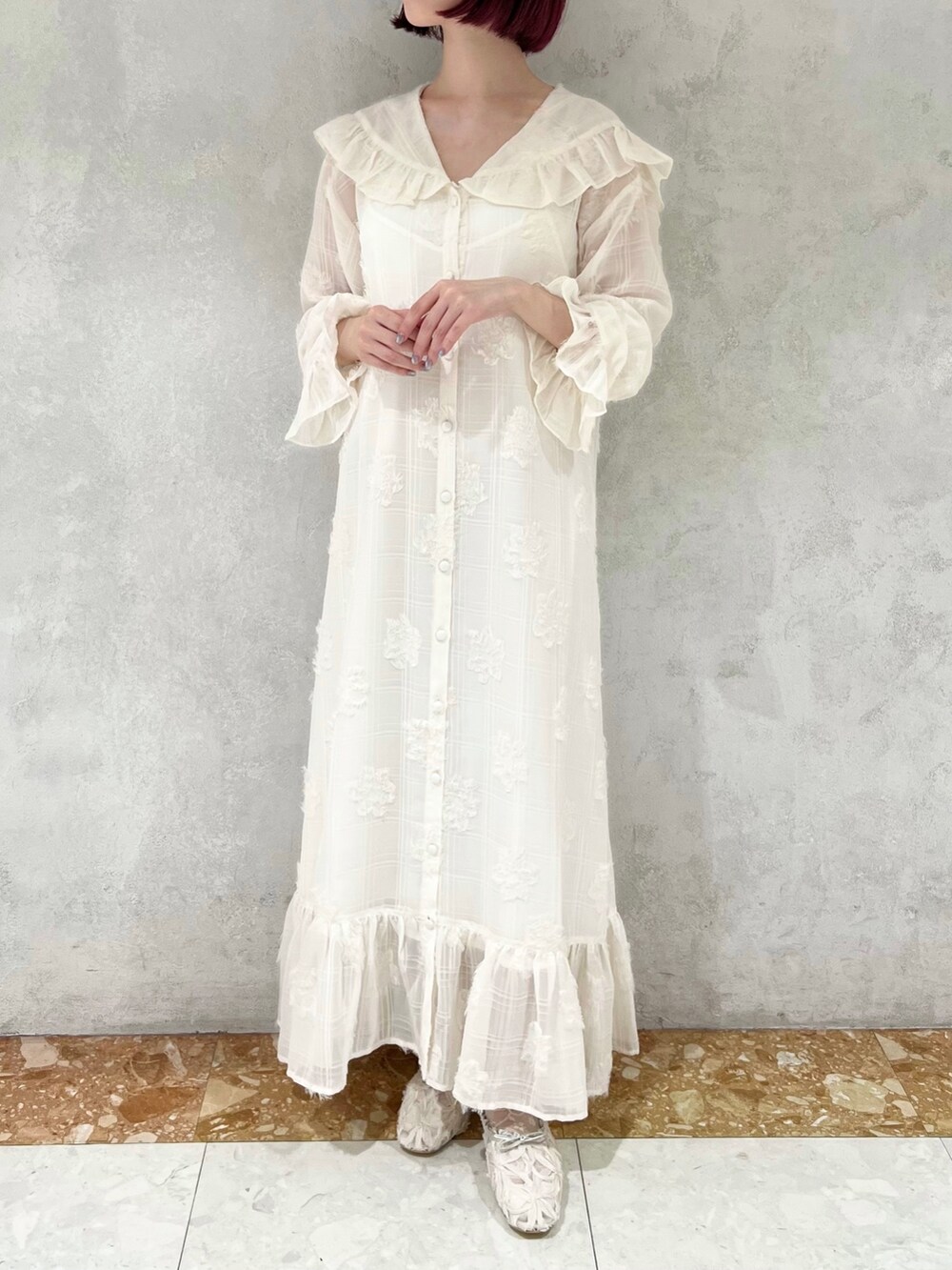 ホワイト系のダウンベスト、グリーン系のパンプス、ホワイト系のワンピースを着用したレディースの冬コーディネートの8枚目の写真