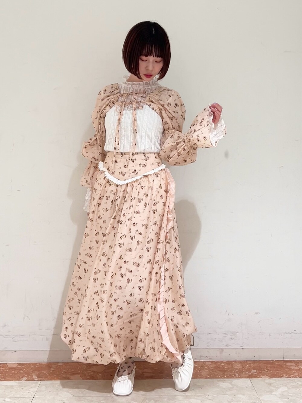 ピンク系のスカート、ピンク系のカーディガン/ボレロ、ホワイト系のパンプスを着用したレディースの春コーディネートの2枚目の写真