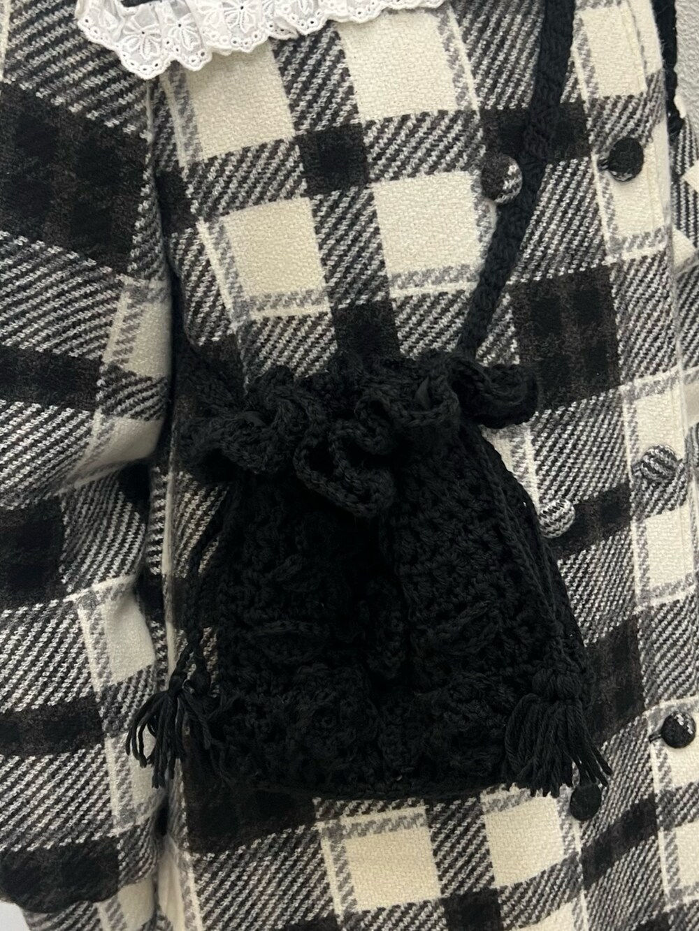 ブラック系のチェスターコート、ホワイト系のニット/セーター、ブラック系のハンドバッグを着用したレディースの秋コーディネートの7枚目の写真