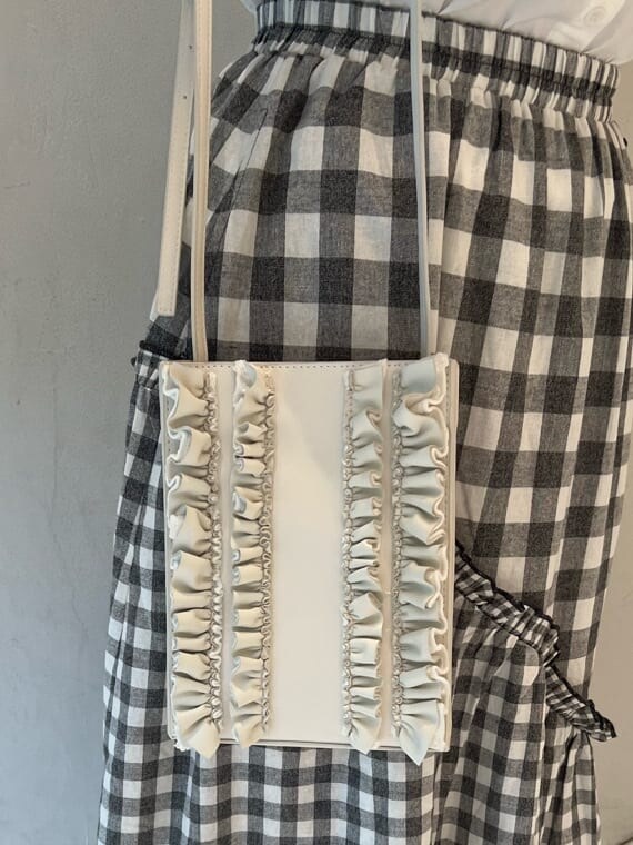 ホワイト系のショルダーバッグ、ブラック系のスカート、ブラック系のサンダルを着用したレディースの夏コーディネートの7枚目の写真