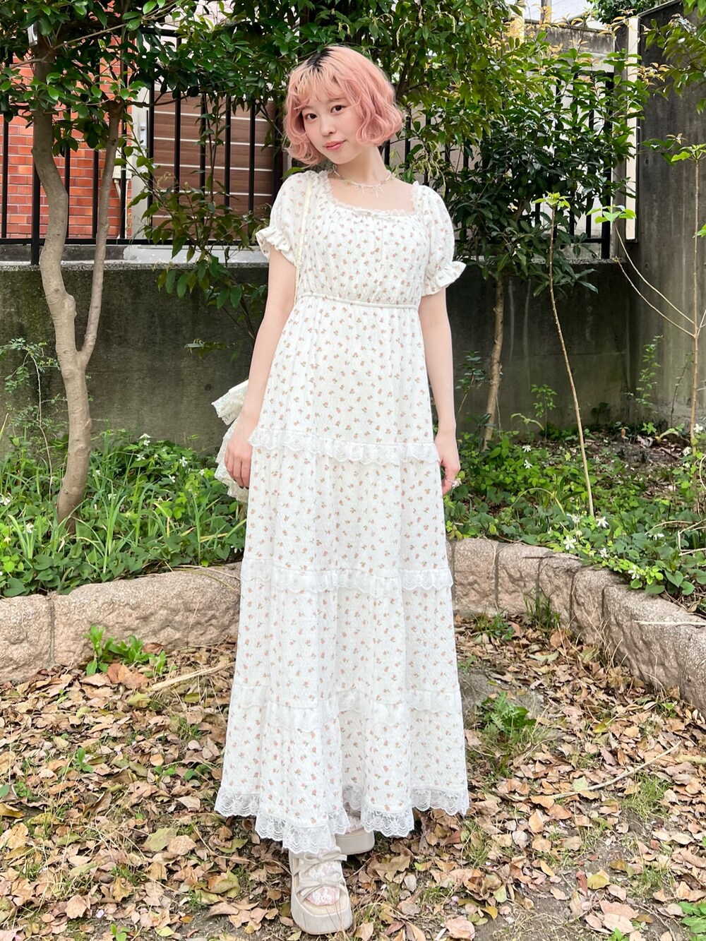 ホワイト系のワンピース、ホワイト系のショルダーバッグ、ベージュ系のサンダルを着用したレディースの春コーディネートの4枚目の写真