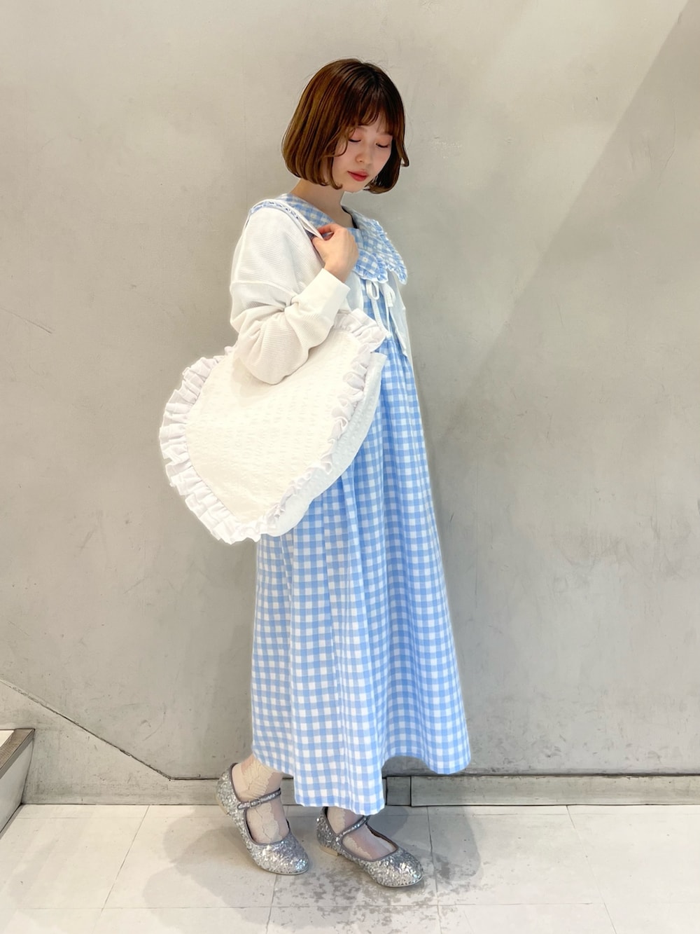 ホワイト系のトートバッグ、シルバー系のパンプス、ブルー系のワンピースを着用したレディースの春コーディネートの3枚目の写真