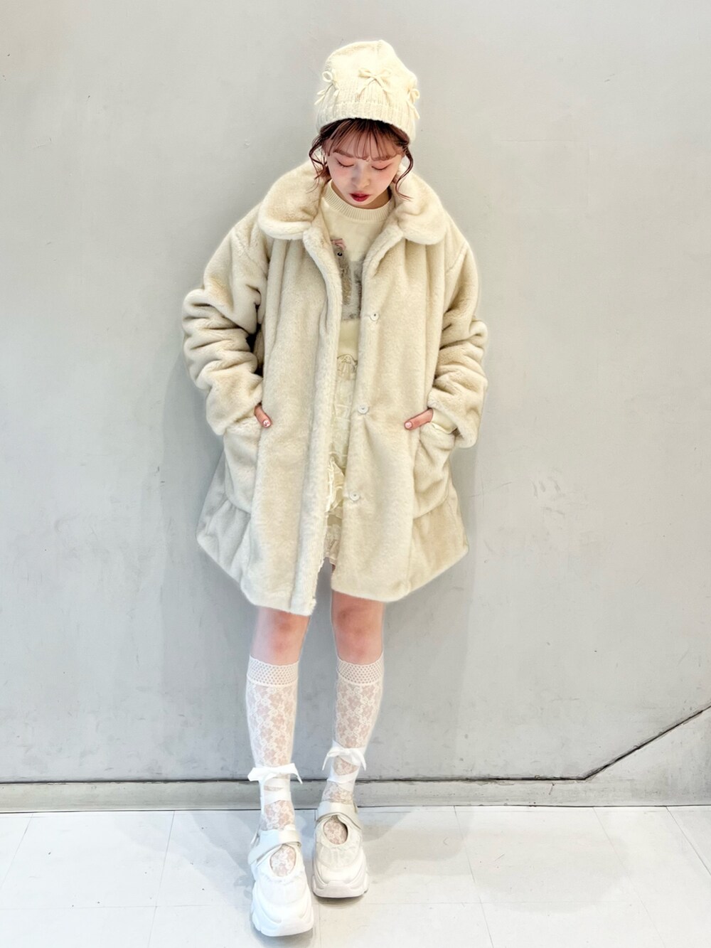 ホワイト系のノーカラーコート、ホワイト系のスカート、ホワイト系のニット/セーターを着用したレディースの冬コーディネートの4枚目の写真