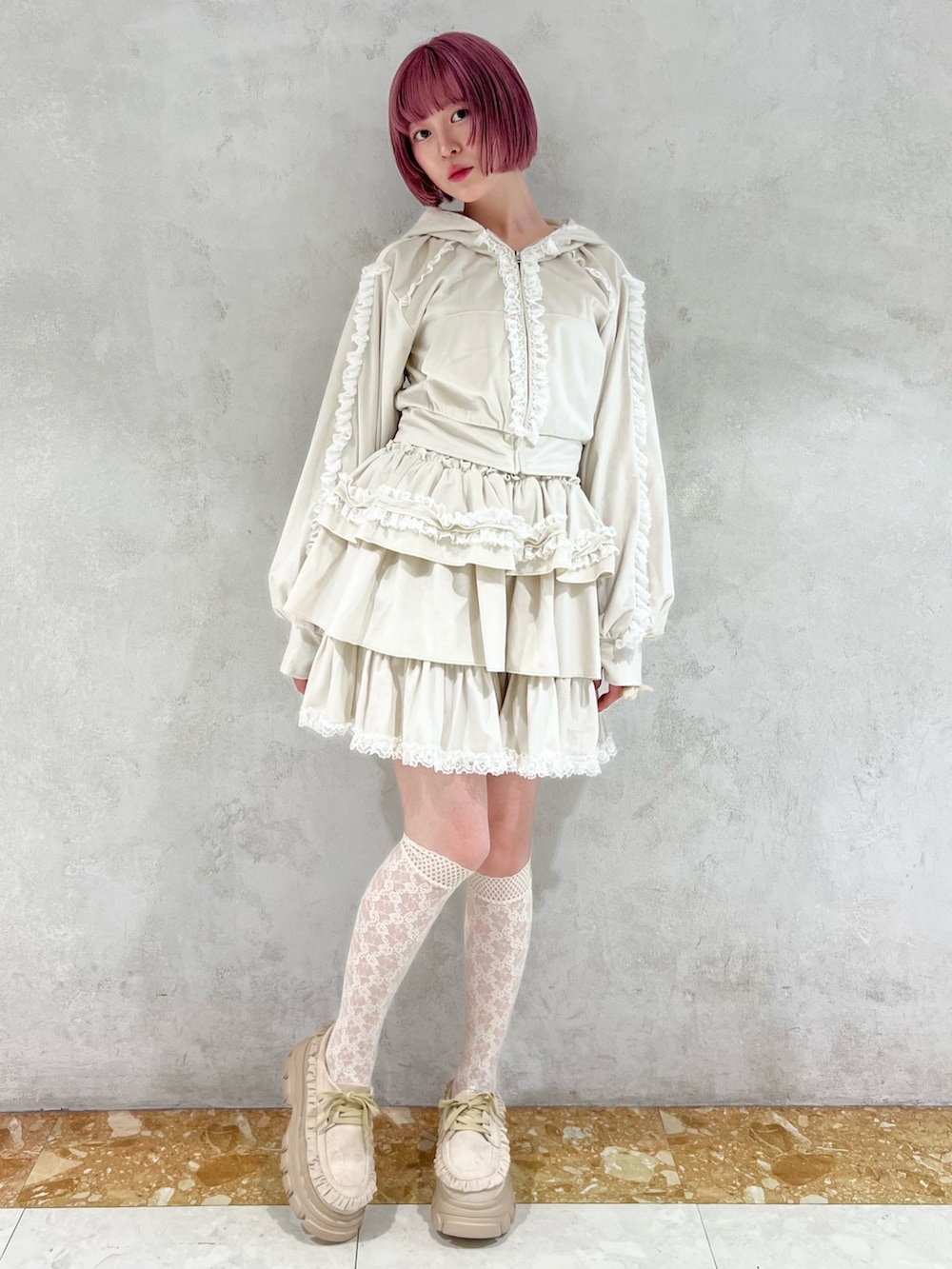 ホワイト系のスカート、ホワイト系のパーカー、ベージュ系のローファーを着用したレディースの秋コーディネートの2枚目の写真