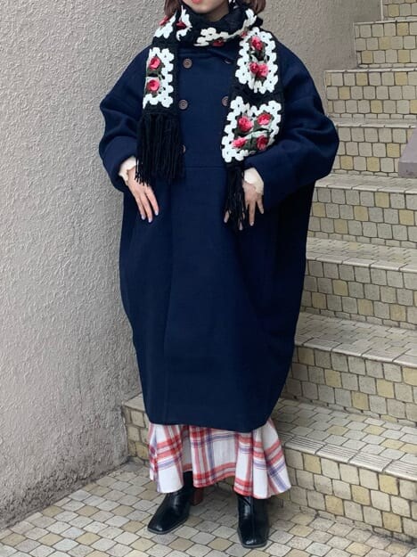 ブルー系のチェスターコート、ホワイト系のニット/セーター、レッド系のスカートを着用したレディースの秋コーディネートの2枚目の写真