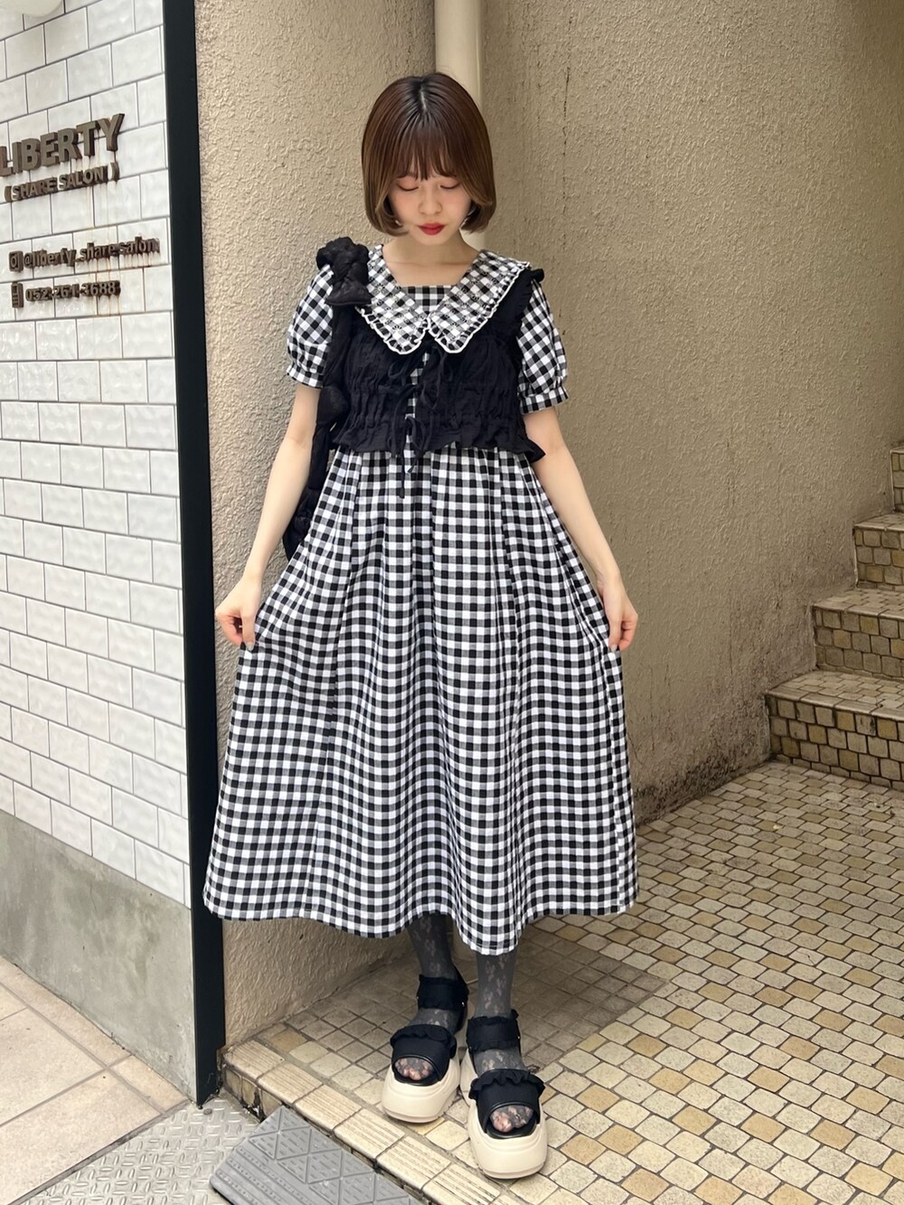 ブラック系のベスト、ブラック系のサンダル、ブラック系のワンピースを着用したレディースの夏コーディネートの4枚目の写真