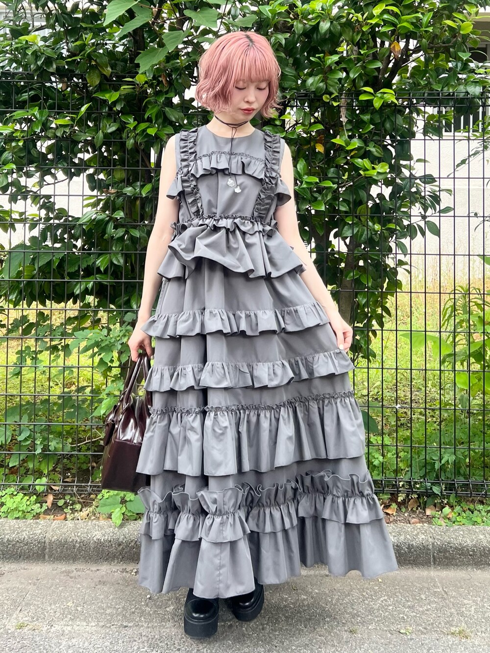 グレー系のワンピース、ブラウン系のハンドバッグ、ブラック系のブーツを着用したレディースの夏コーディネートの4枚目の写真
