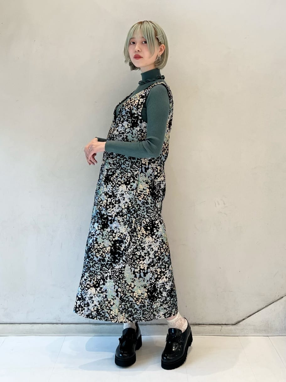 グリーン系のニット/セーター、ブラック系のワンピース、ブラック系のローファーを着用したレディースの秋コーディネートの3枚目の写真