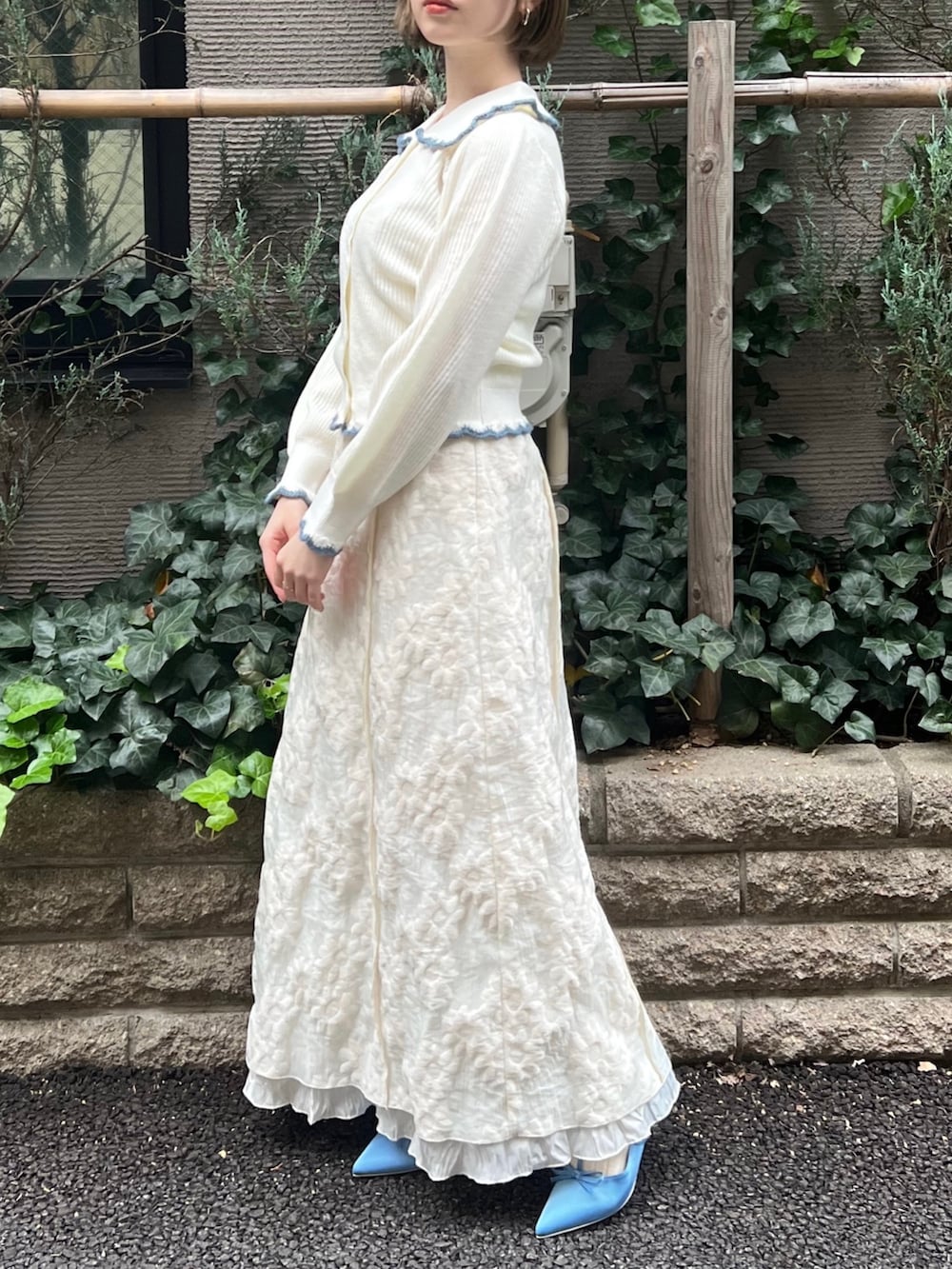 ホワイト系のニット/セーター、ホワイト系のワンピース、ブルー系のパンプスを着用したレディースの冬コーディネートの2枚目の写真