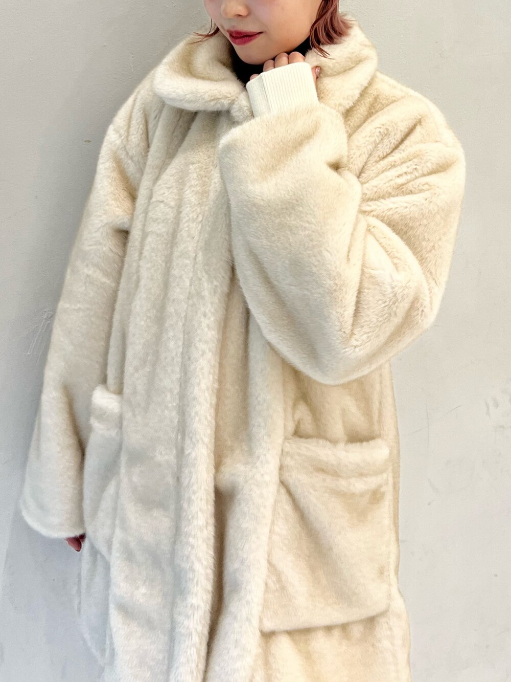 ホワイト系のノーカラーコート、ホワイト系のスカート、ホワイト系のニット/セーターを着用したレディースの冬コーディネートの8枚目の写真