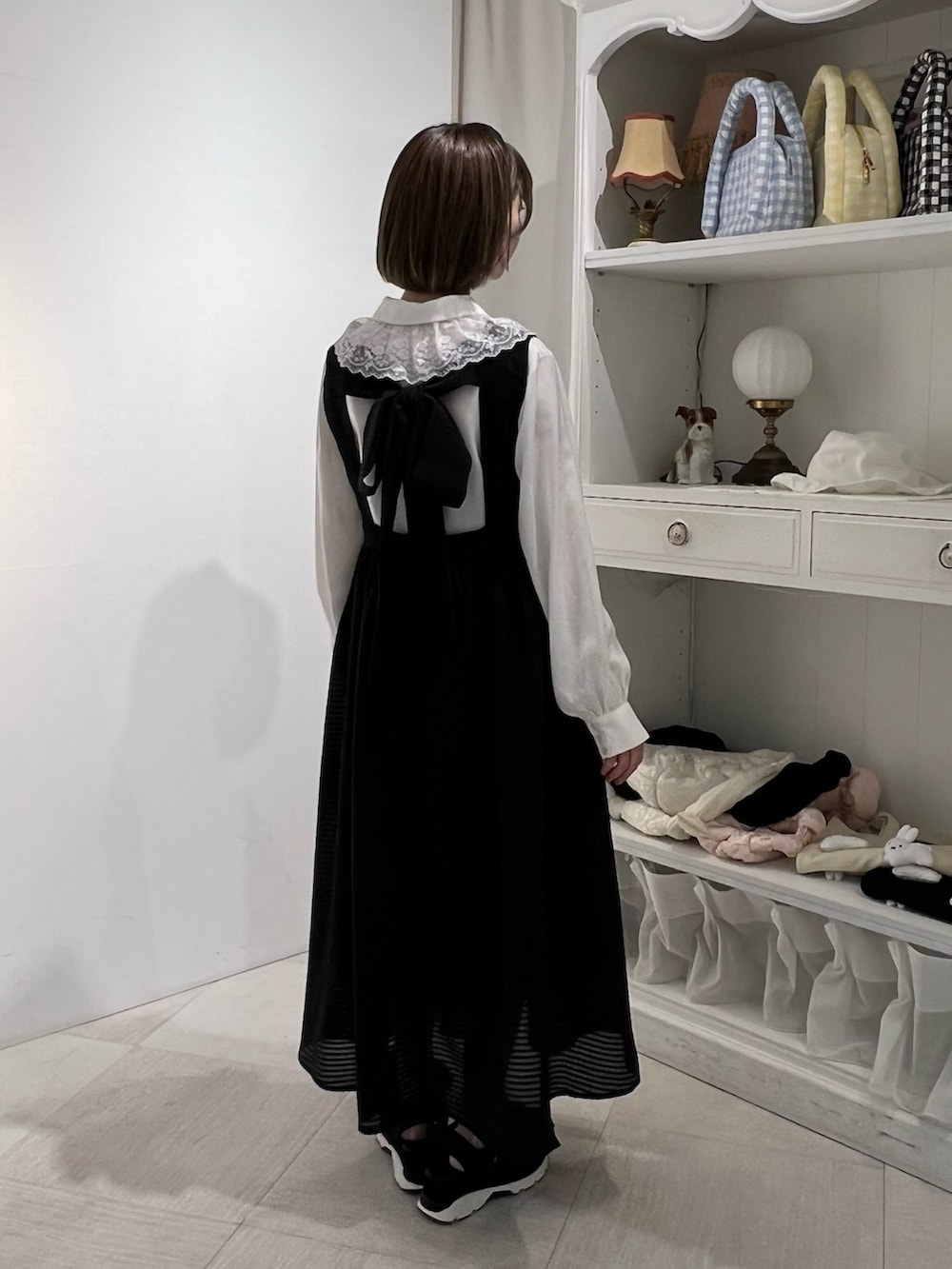 ホワイト系のチュニック、ブラック系のサンダル、ブラック系のワンピースを着用したレディースの春コーディネートの4枚目の写真