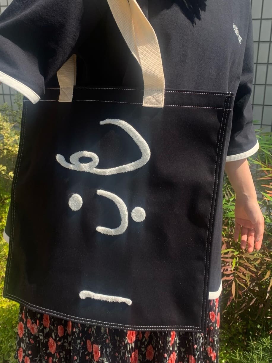 ブラック系のパンプス、ブラック系のスカート、ブラック系のトートバッグを着用したレディースの春コーディネートの7枚目の写真