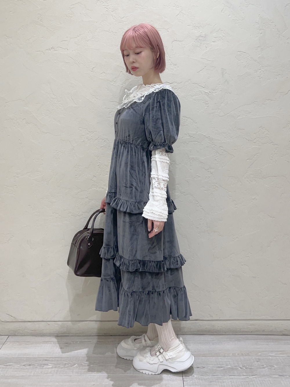 グレー系のワンピース、ブラウン系のハンドバッグ、ホワイト系のスニーカーを着用したレディースの夏コーディネートの3枚目の写真