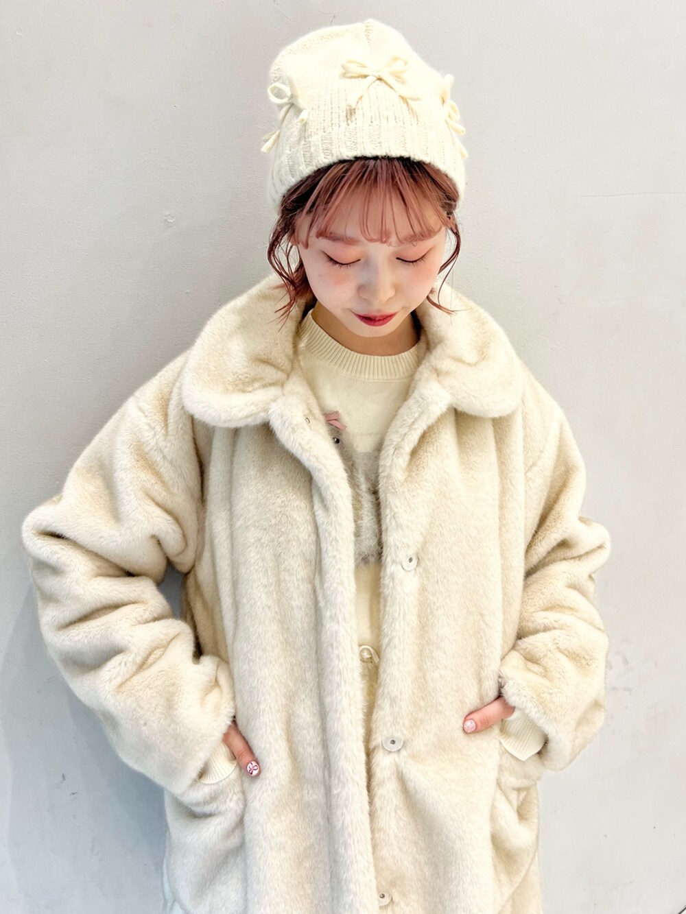 ホワイト系のノーカラーコート、ホワイト系のスカート、ホワイト系のニット/セーターを着用したレディースの冬コーディネートの6枚目の写真