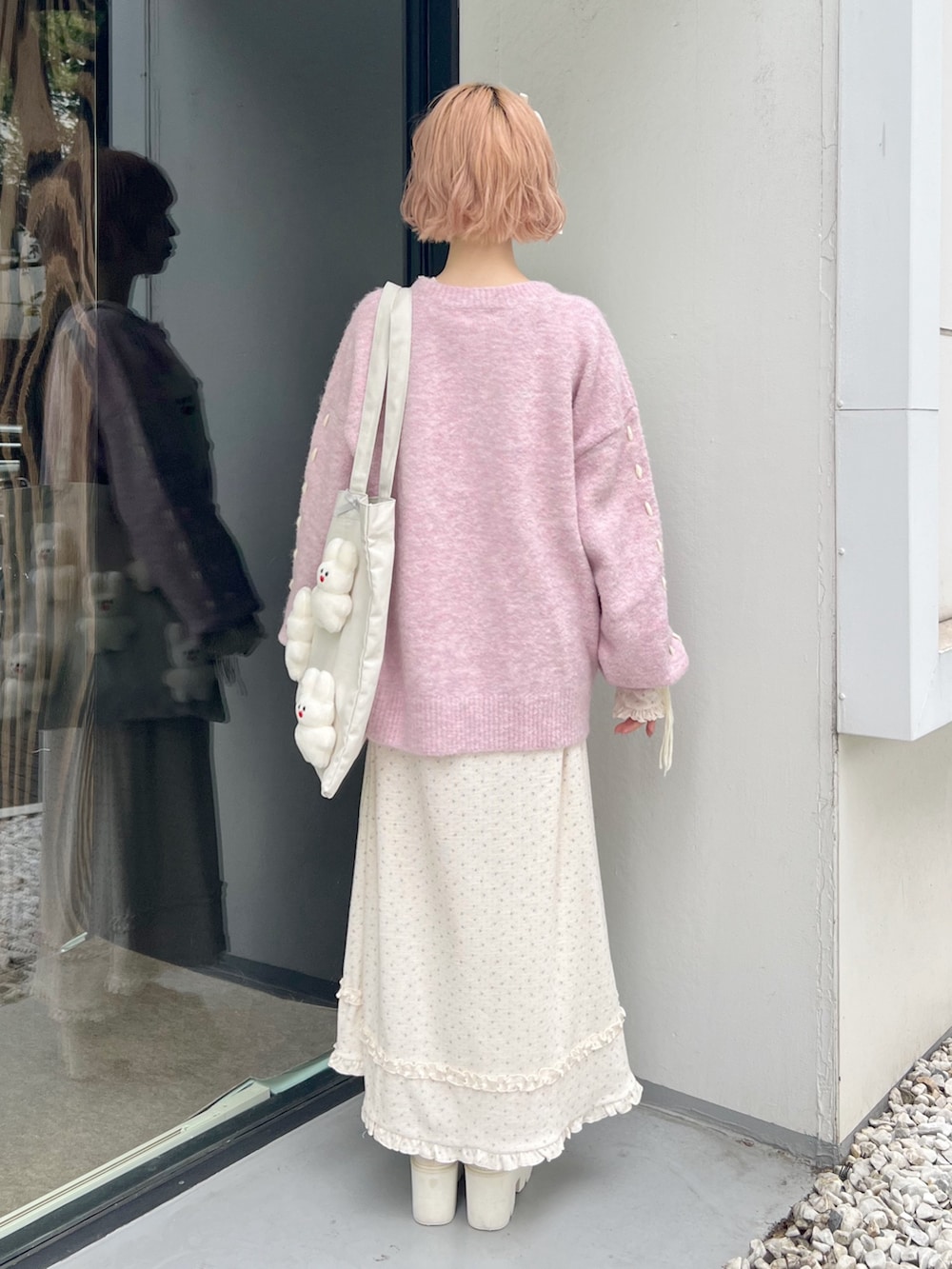 ホワイト系のブーツ、ピンク系のカーディガン/ボレロ、ホワイト系のトートバッグを着用したレディースの秋コーディネートの3枚目の写真