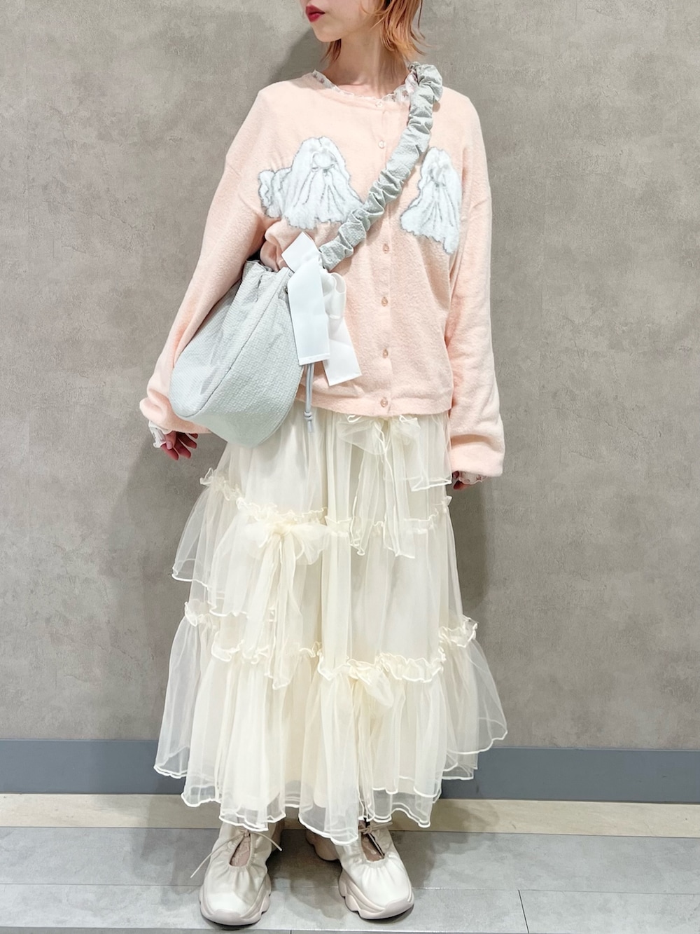 ピンク系のTシャツ/カットソー、ホワイト系のスカート、ホワイト系のスニーカーを着用したレディースの秋コーディネートの2枚目の写真