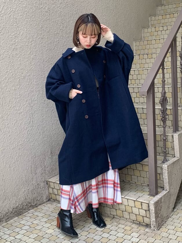 ブルー系のチェスターコート、ホワイト系のニット/セーター、レッド系のスカートを着用したレディースの秋コーディネートの4枚目の写真