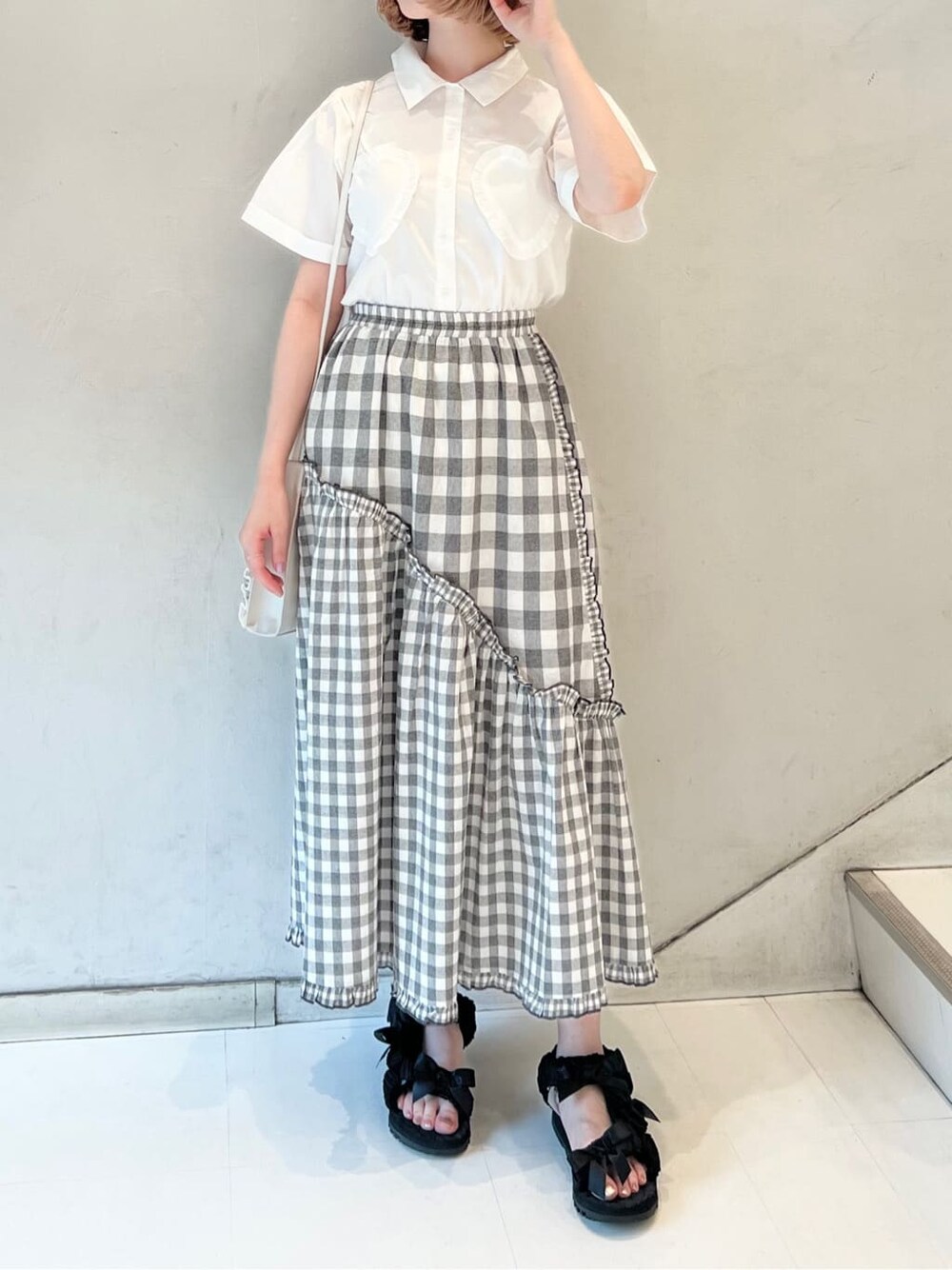 ホワイト系のショルダーバッグ、ブラック系のスカート、ブラック系のサンダルを着用したレディースの夏コーディネートの4枚目の写真