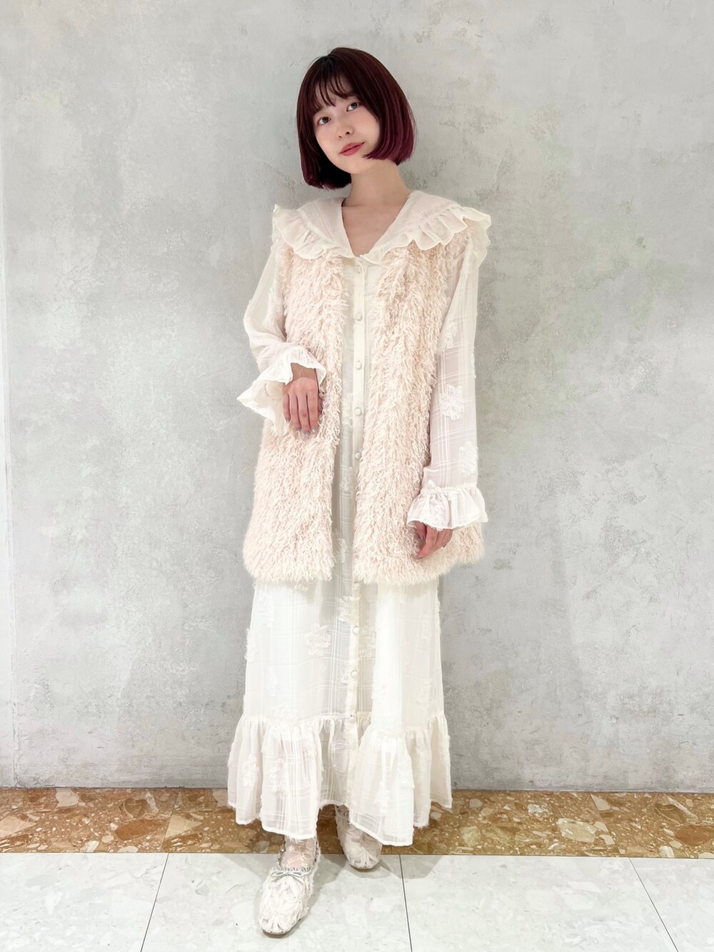 ホワイト系のダウンベスト、グリーン系のパンプス、ホワイト系のワンピースを着用したレディースの冬コーディネートの6枚目の写真