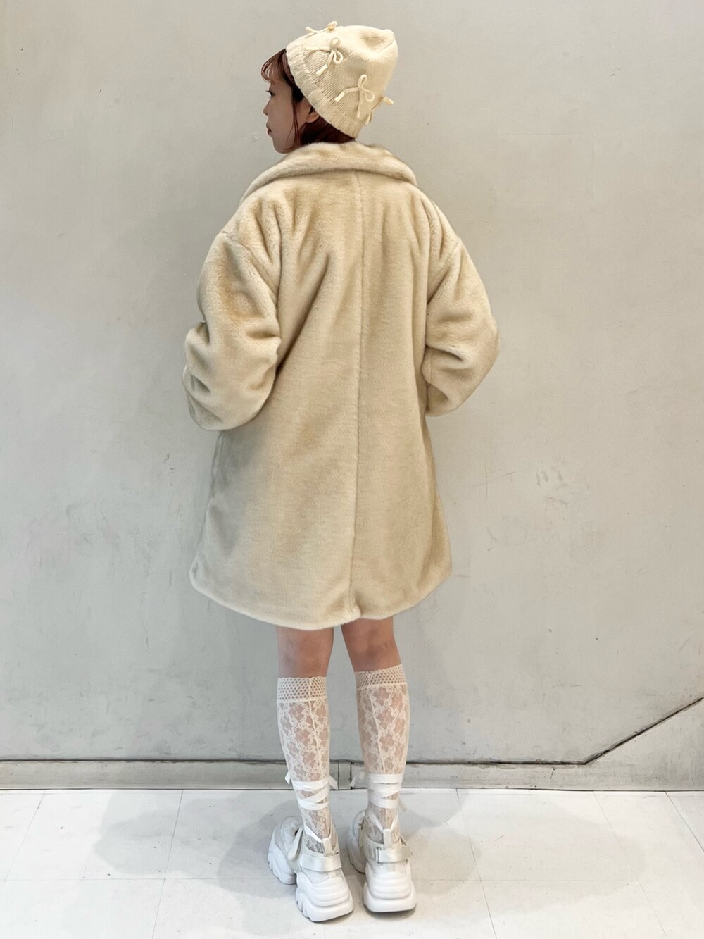 ホワイト系のノーカラーコート、ホワイト系のスカート、ホワイト系のニット/セーターを着用したレディースの冬コーディネートの5枚目の写真