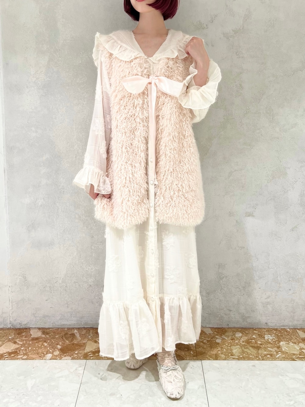 ホワイト系のダウンベスト、グリーン系のパンプス、ホワイト系のワンピースを着用したレディースの冬コーディネートの4枚目の写真