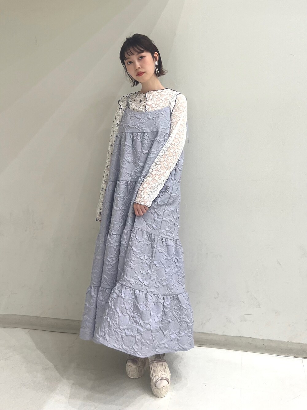 パープル系のワンピース、ホワイト系のTシャツ/カットソー、ホワイト系のサンダルを着用したレディースの夏コーディネートの2枚目の写真