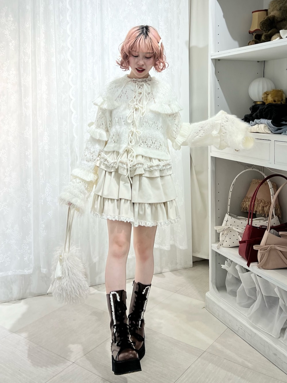 ホワイト系のボストンバッグ、ブラウン系のブーツ、ホワイト系のスカートを着用したレディースの夏コーディネートの2枚目の写真