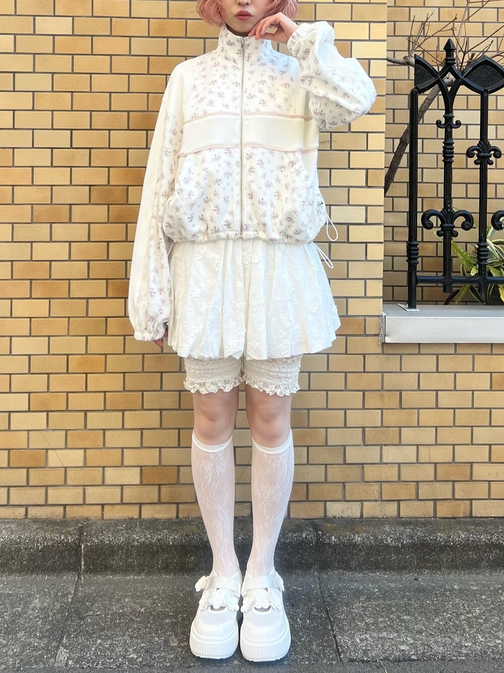 ピンク系のジャージ、ホワイト系のスカート、ホワイト系のスニーカーを着用したレディースの冬コーディネートの2枚目の写真