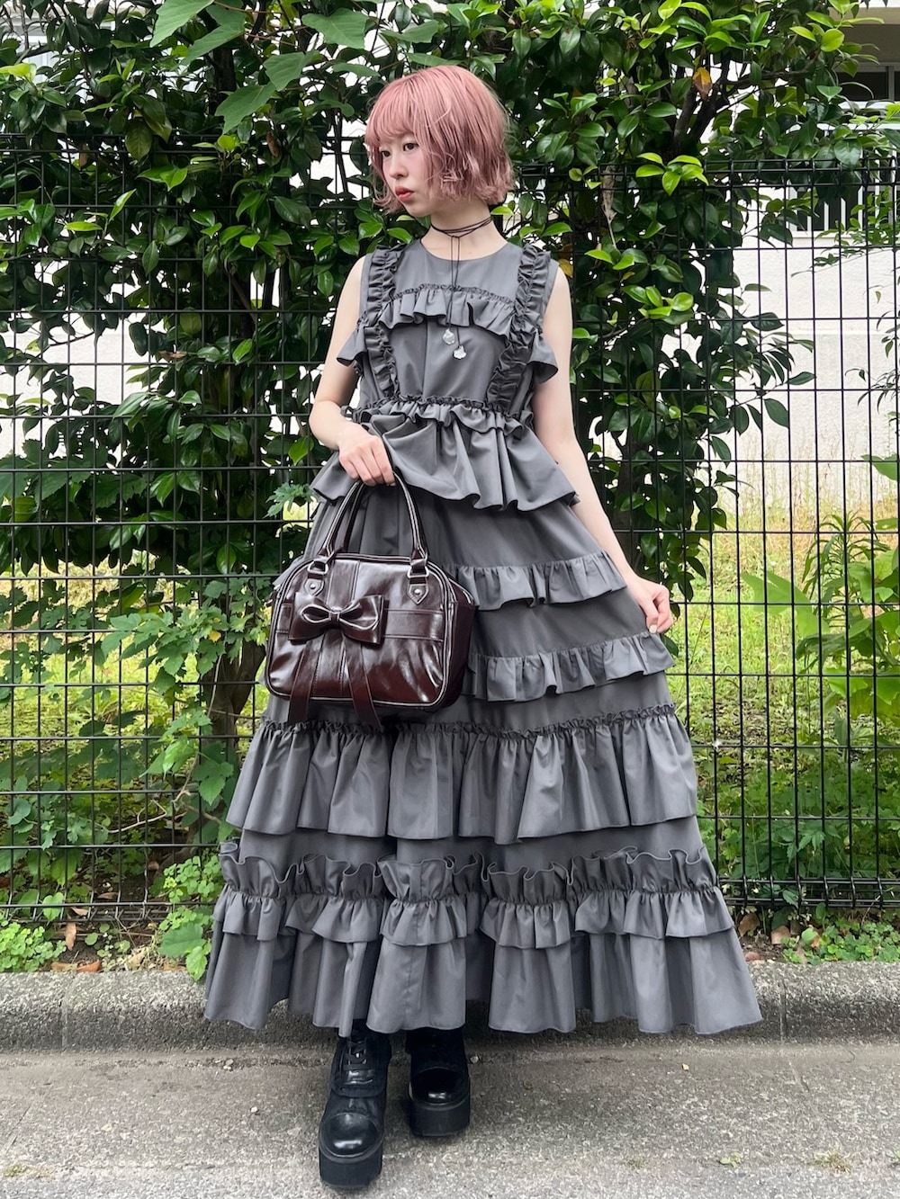 グレー系のワンピース、ブラウン系のハンドバッグ、ブラック系のブーツを着用したレディースの夏コーディネートの2枚目の写真