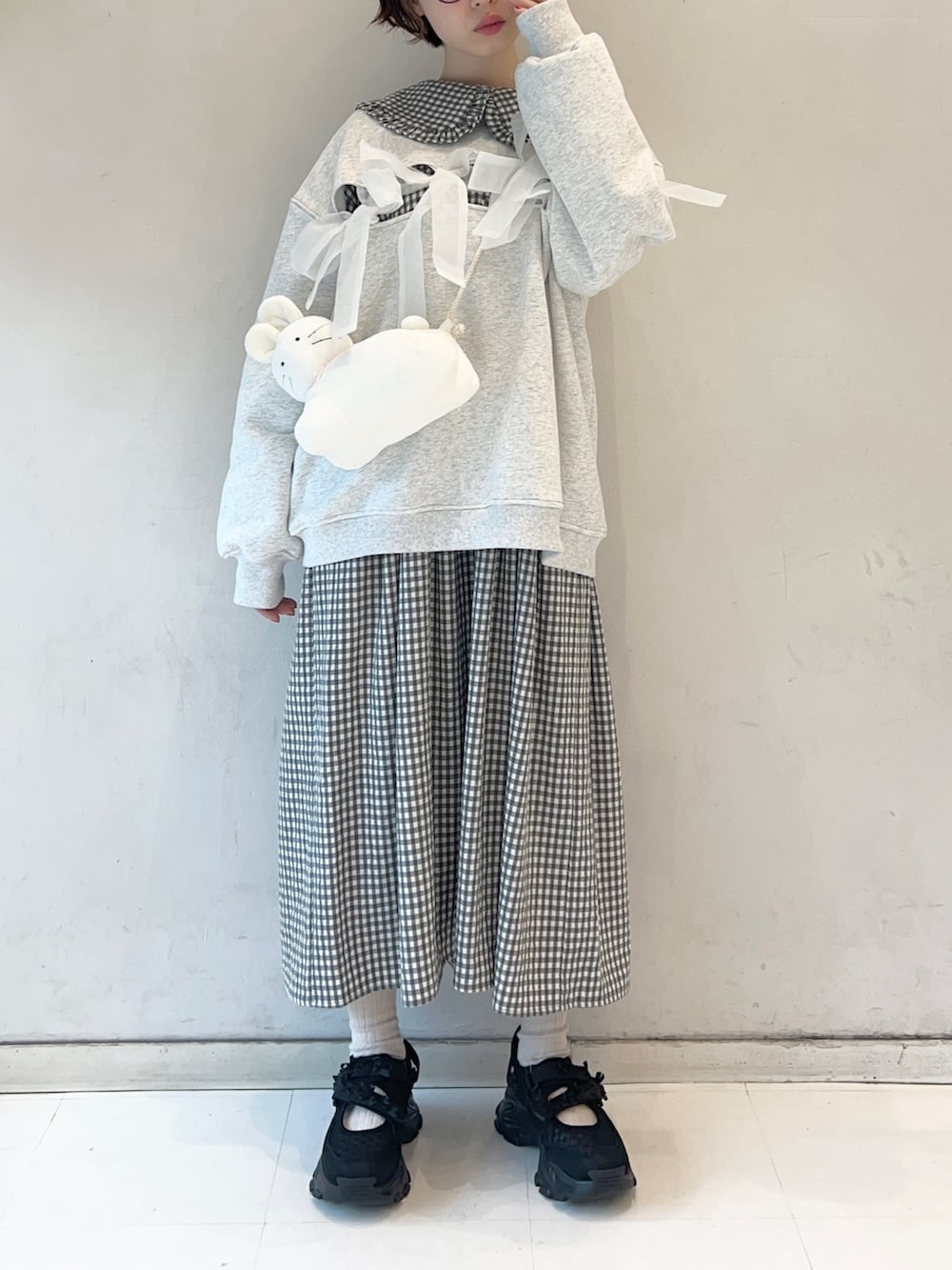 ブラック系のワンピース、ブラック系のスニーカー、ホワイト系のショルダーバッグを着用したレディースの冬コーディネートの2枚目の写真