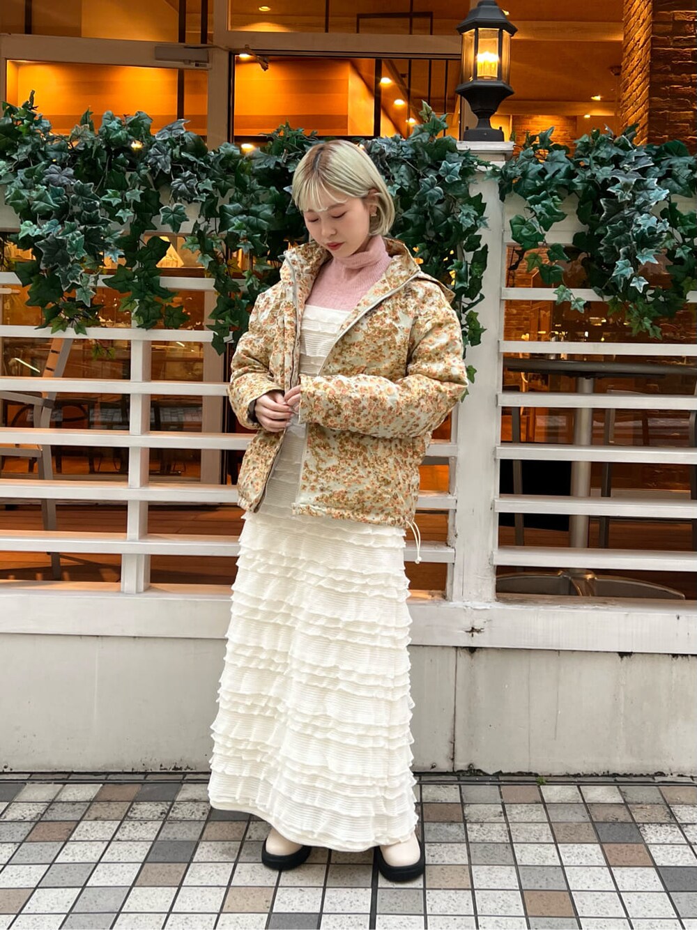 イエロー系のマウンテンパーカー、ホワイト系のブーツ、ホワイト系のワンピースを着用したレディースの秋コーディネートの2枚目の写真