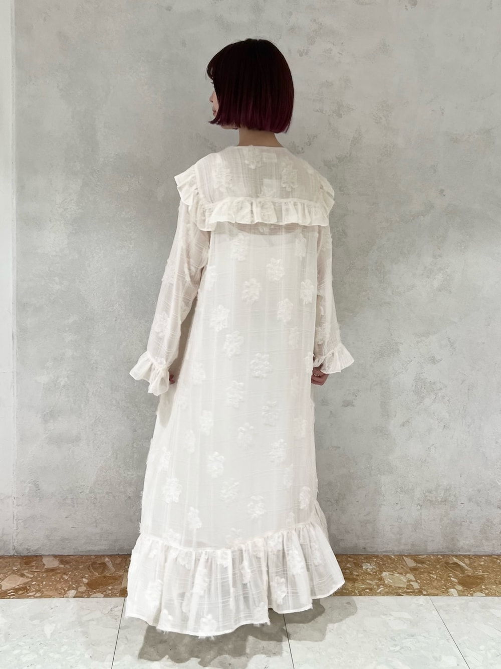 ホワイト系のダウンベスト、グリーン系のパンプス、ホワイト系のワンピースを着用したレディースの冬コーディネートの9枚目の写真