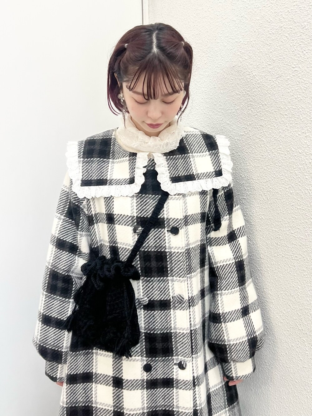 ブラック系のチェスターコート、ホワイト系のニット/セーター、ブラック系のハンドバッグを着用したレディースの秋コーディネートの5枚目の写真