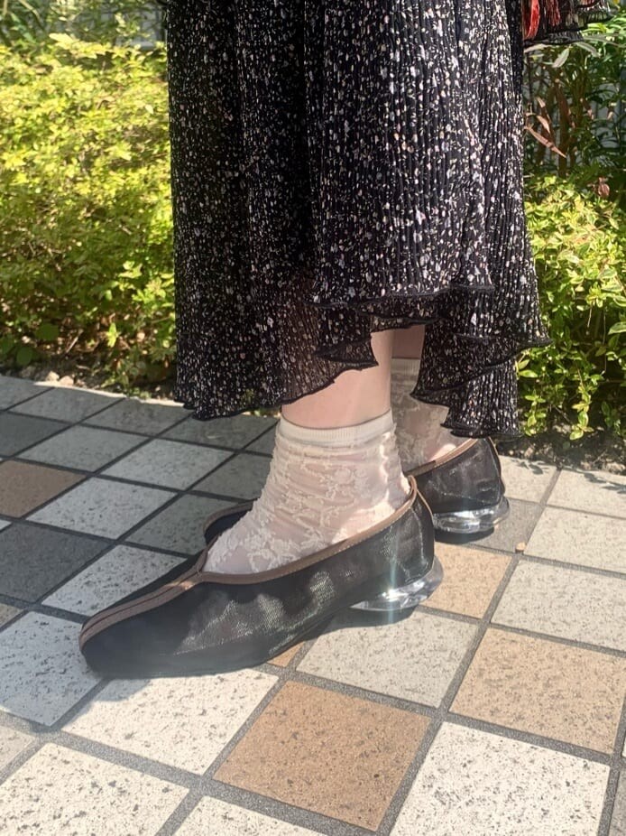 ブラック系のパンプス、ブラック系のスカート、ブラック系のトートバッグを着用したレディースの春コーディネートの8枚目の写真