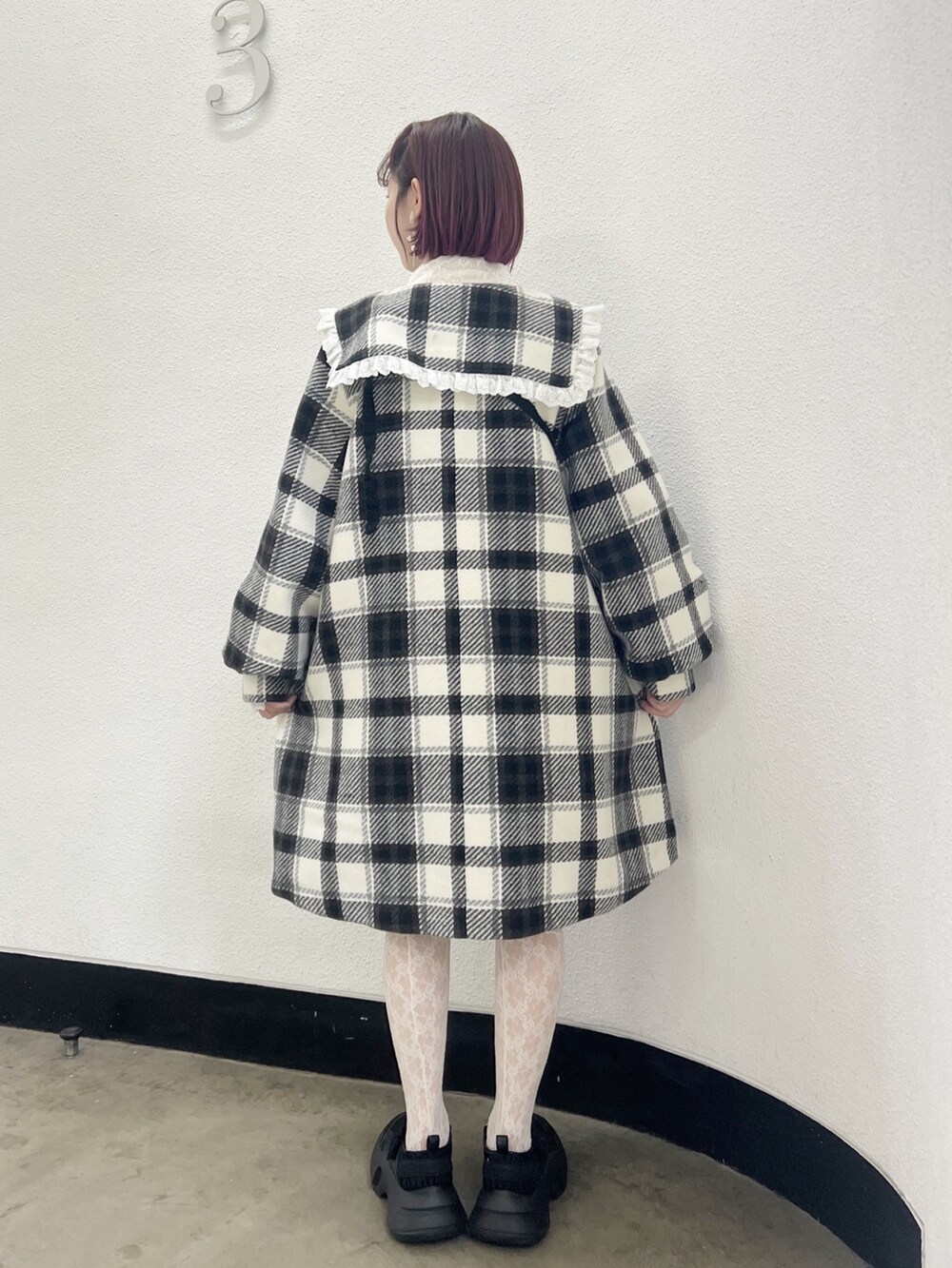 ブラック系のチェスターコート、ホワイト系のニット/セーター、ブラック系のハンドバッグを着用したレディースの秋コーディネートの4枚目の写真