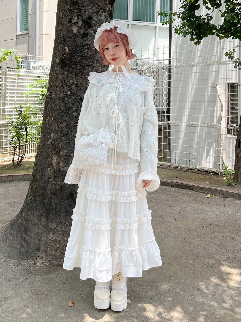 ホワイト系のハンドバッグ、ホワイト系のスカート、ホワイト系のブーツを着用したレディースの夏コーディネートの3枚目の写真